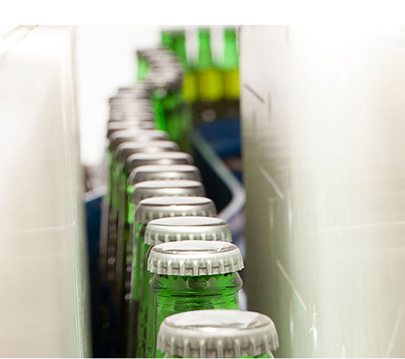 close up of glass bottles with caps on a conveyor line